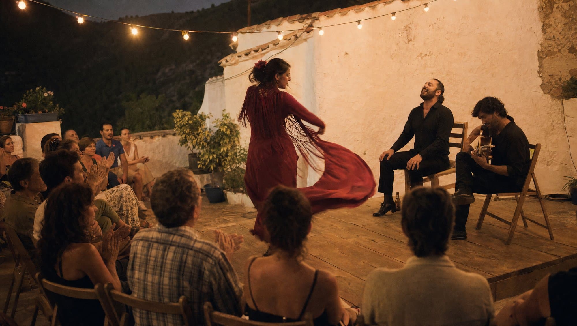 A flamenco dancer in a red dress turning on a wooden stage in a whitewashed Andalusian village courtyard at night, guitarist and singer seated beside her
